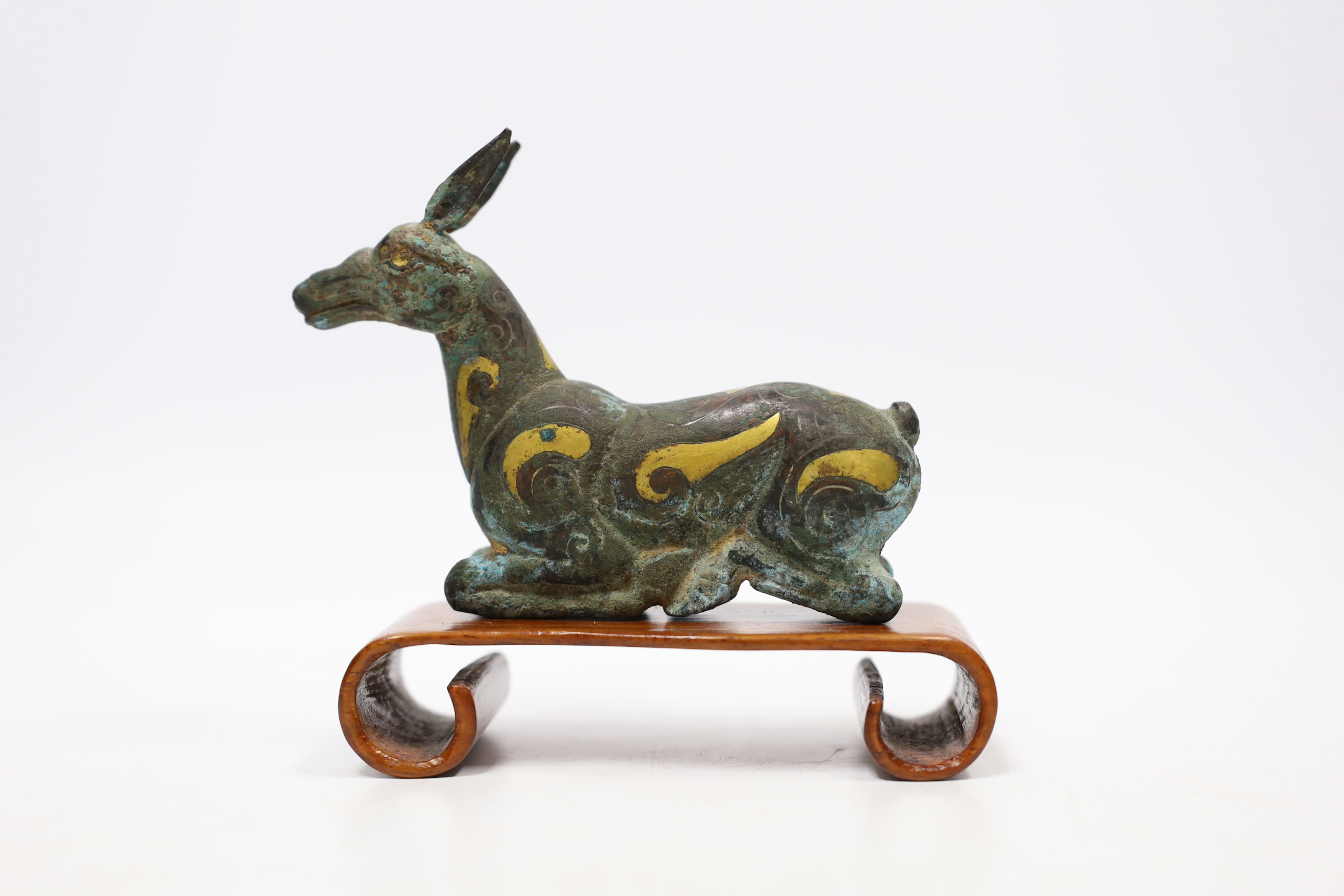 A Chinese bronze and parcel gilt Han style figure of a seated deer, and a small Etruscan terracotta head on stand